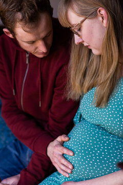Young husband touching wife's pregnant belly - lifestyle maternity