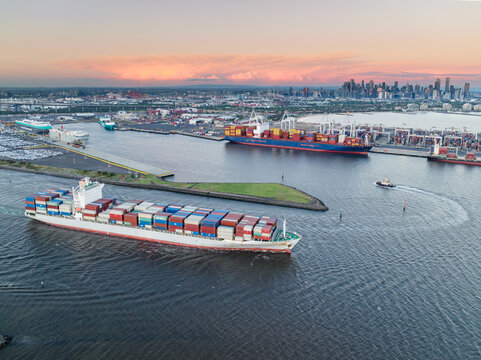 Aerial view of a cargo ship leaving port fully laden with containers