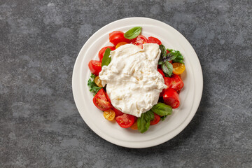 Italian salad cheese burrata or stracciatella with tomatoes on a plate. Top view