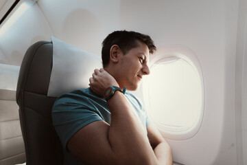 A man suffers from severe neck pain during a long flight in an uncomfortable position on an airplane. Osteochondrosis symptoms and causes