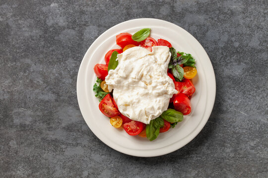 Italian salad cheese burrata or stracciatella with tomatoes on a plate. Top view