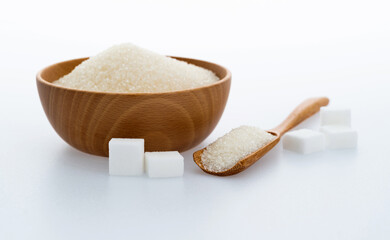A bowl granulated sugar and sugar cubes on white background