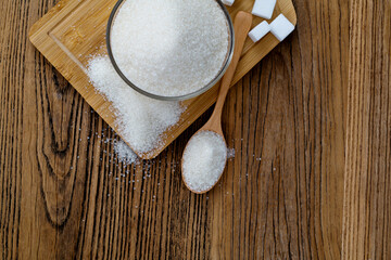 A bowl granulated sugar and sugar cubes on the board