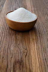 Granulated sugar in a bowl on wooden table