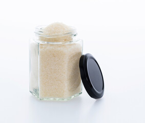 Granulated sugar in glass jar on white background