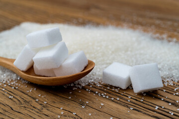 Spoon with sugar cubes on top of granulated sugar