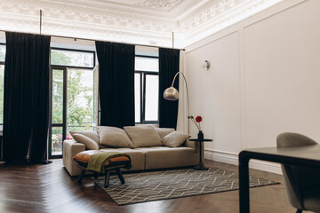 an example of a living room interior in a neo-classical style with modern elements. a sofa in the middle of a room with high ceilings and moldings.	
