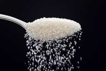 Sugar crystals falling out of metal spoon