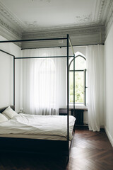interior design of a bedroom in a classic style with modern elements. bedroom in an old house with high ceilings and stucco	