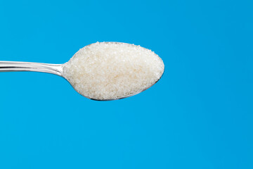 Spoon with sugar crystals on black background