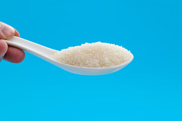 Hand holding ceramic spoon with sugar crystals