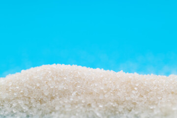 Pile of white sugar crystals on blue background