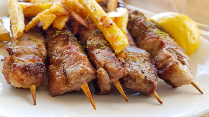suvlaki or suvlakia with potatoes on the plate in greece