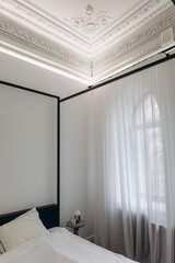 interior design of a bedroom in a classic style with modern elements. bedroom in an old house with high ceilings and stucco
