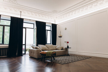 an example of a living room interior in a neo-classical style with modern elements. a sofa in the middle of a room with high ceilings and moldings.