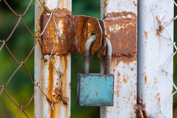 Old gates with peeling paint, locked with locks and rusty old chains around them - Old metal gates with locks on which hang several chains - Locked gates. Restricted area.