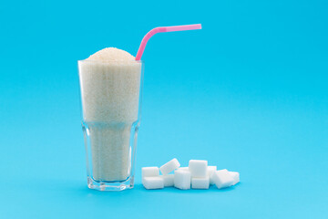 Glass cup full of sugar crystals on blue background