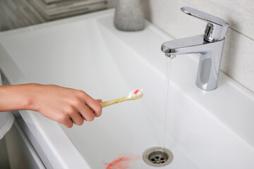 Blood on toothbrush on background of sink. Selective focus on the toothbrush.