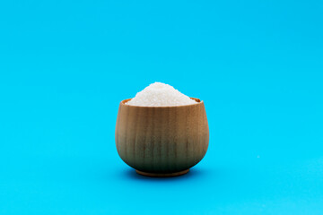 Fototapeta na wymiar Granulated sugar in a bowl on blue background