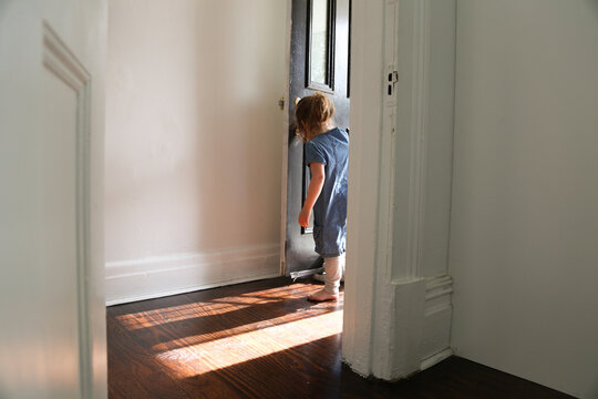 Girl Wearing Blue Dress And Grey Pants  Going Inside The House With Shadows From The Door