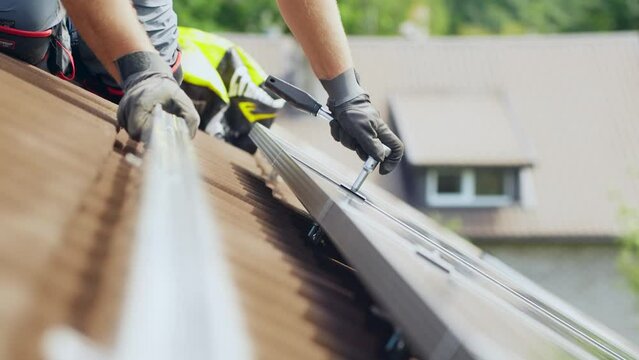 Handyman using tools to fix solar panel on rooftop, side view