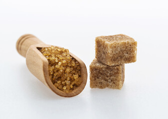 Wooden scoop of brown sugar on white background
