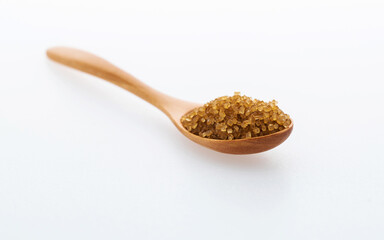Wooden spoon of brown sugar on white background