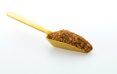 Metal scoop of brown sugar on white background