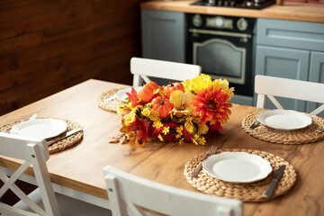 Cozy table setting with fall decor, flowers and utensils in dining room. Bouquet of fall flowers....