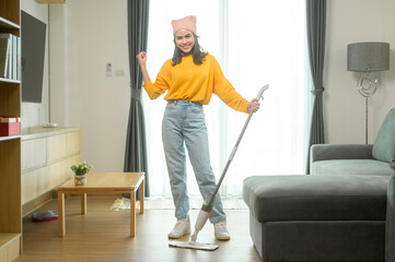 Young happy woman mopping and vacuum the floor in living room.
