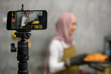 Beautiful muslim woman is making bakery while live streaming or recording video on social media in...