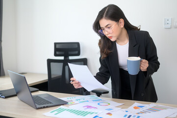 Young beautiful business woman working on laptop with documents in modern office