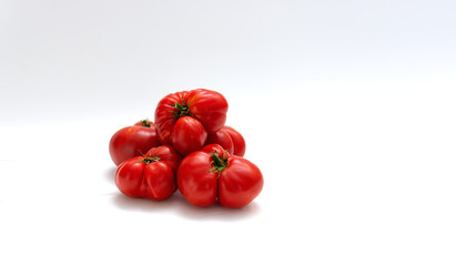 Several red tomatoes lie on a white background in a slide. Ugly vegetables.