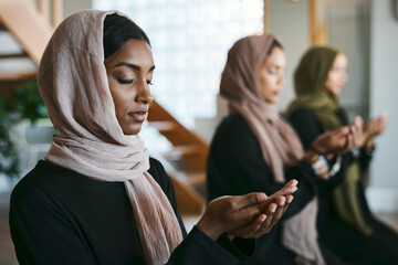 Praying, muslim and young women group practicing arabic, holy and islamic religion indoors. Females wearing a hijab while kneeling to practice a quiet, spiritual and worship prayer inside in silence - obrazy, fototapety, plakaty