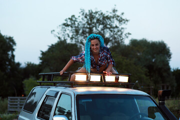 Woman with blue hair on a roof of a car