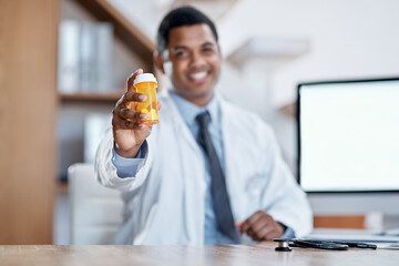 Happy, joyful and friendly male medical doctor offers a bottle of pills to a client with a smile....