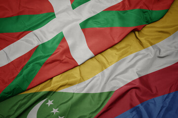 waving colorful flag of comoros and national flag of basque country.