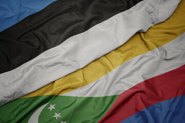 waving colorful flag of comoros and national flag of estonia.