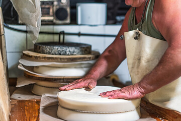 An alpine dairyman during the creation of the typical local Bergamasque northern Italian cheese wheel