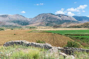 Idyllic landscape with agricultural fields surrounded by mountains in southern Albania near the abandoned Orthodox monastery - 523991448