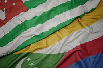 Obraz premium waving colorful flag of comoros and national flag of abkhazia.