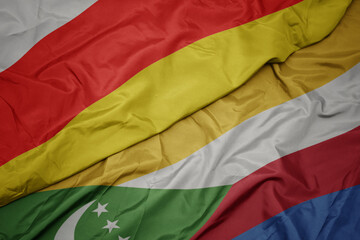 waving colorful flag of comoros and national flag of south ossetia.
