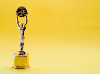 Golden statuette of a man on yellow background