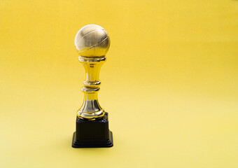 Golden basketball trophy on yellow background
