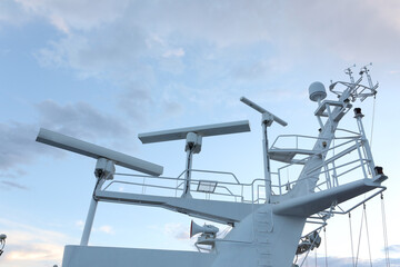 Ship structures, masts, antennas, funnel, ship wheelhouse against the blue sky and clouds. Vessel traveling at ocean. © AJITH.A