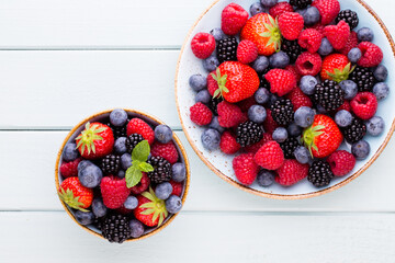 Fresh berry salad on blue dishes. Vintage wooden background.