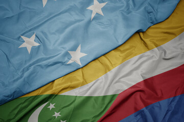 waving colorful flag of comoros and national flag of Federated States of Micronesia .