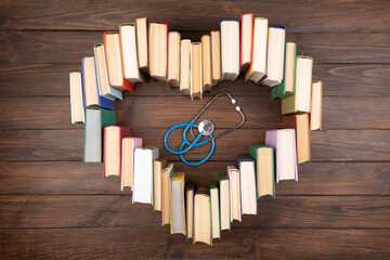 Medical degree education concept - stack of books in heart shape and stethoscope on the library table. Love to study medicine - obrazy, fototapety, plakaty