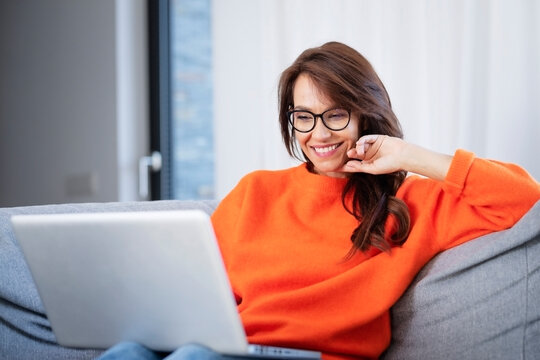 Happy woman using laptop while sitting at home