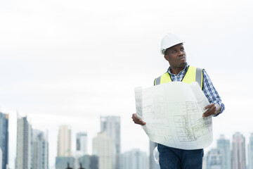 African American male engineer working with building blueprint for checks or maintenance at...